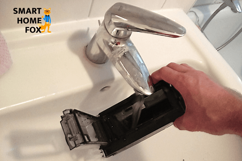 Der Schmutzbehälter des Roborock Saugroboters wird unter fließendem Wasser ausgewaschen